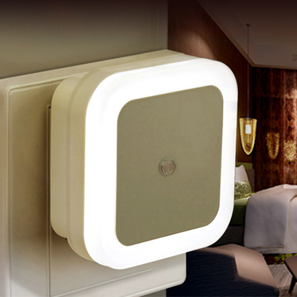 Belro plug-in motion detector smart outlet night light plugged into a wall socket, emitting soft illumination in a dark room.