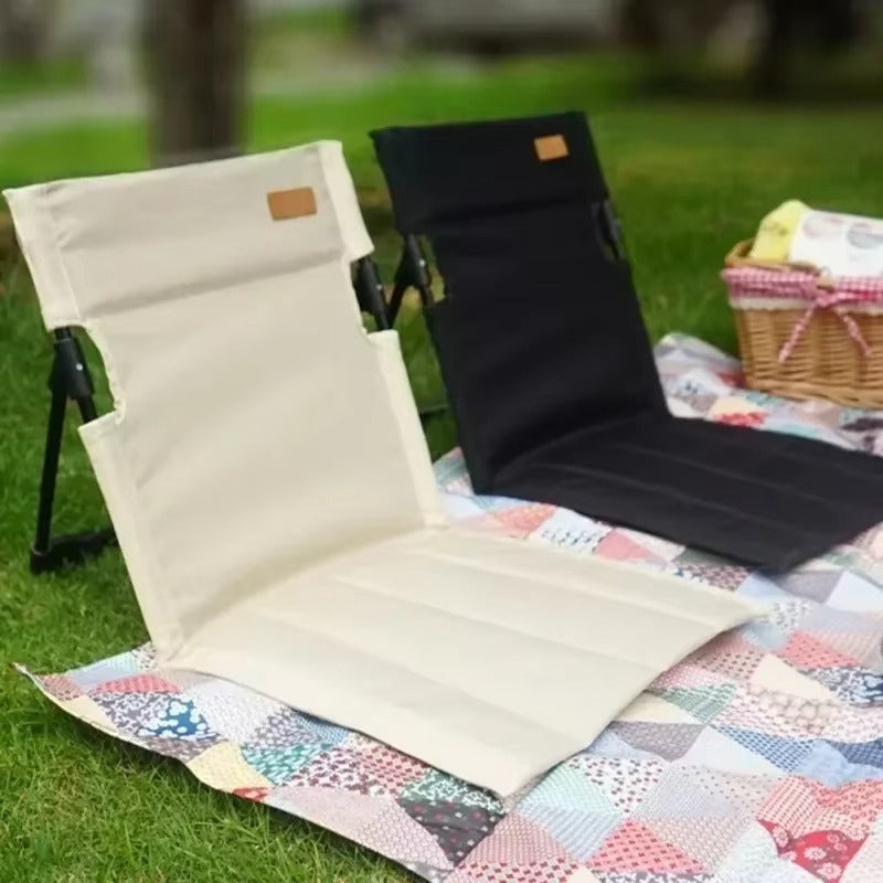 Mivoza foldable outdoor floor chair with back support, ideal for camping and picnics, shown in a garden setting.
