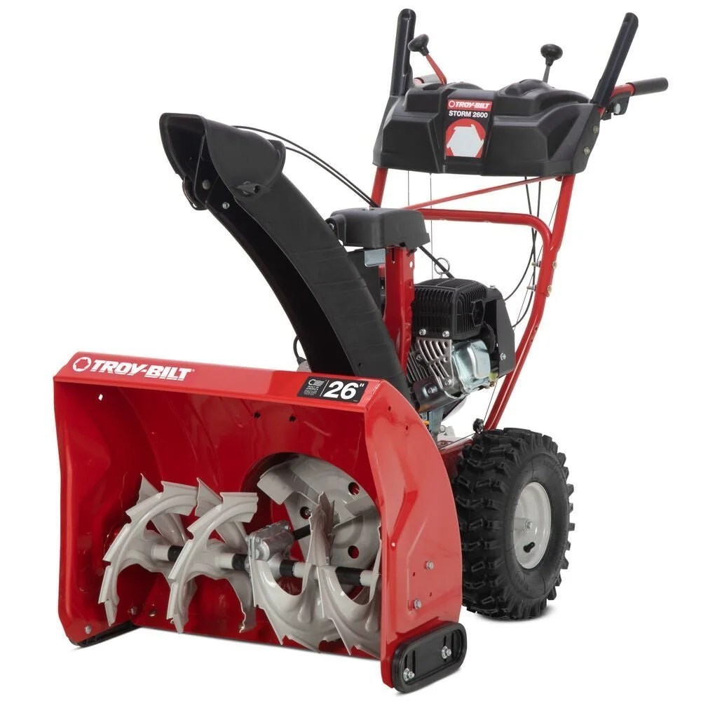 Casavibeo Troy-Bilt Storm 2600 26-inch two-stage gas snow blower with electric start, showing its auger and chute in winter snow.