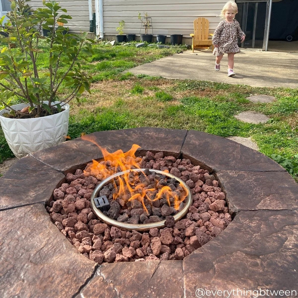 Red Barrel Studio Kimily propane outdoor fire pit by Casavibeo with a round metal design and burning flames on a patio setting.
