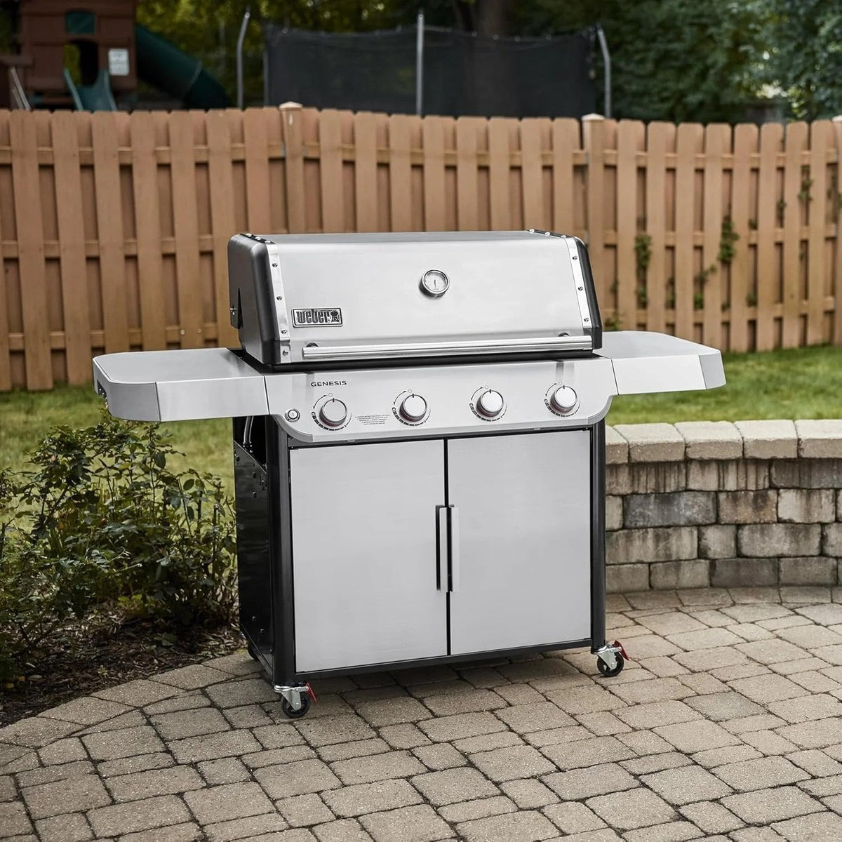 Casavibeo Weber Genesis S-415 natural gas grill with four burners, stainless steel lid, side shelves, and control knobs.