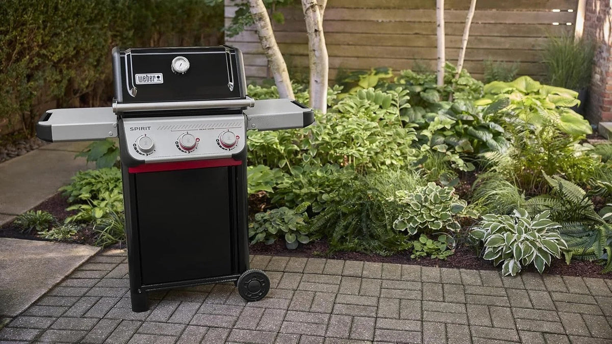 Casavibeo Weber Spirit E-325 gas grill with stainless steel lid, side shelves, and multiple burners for outdoor cooking.