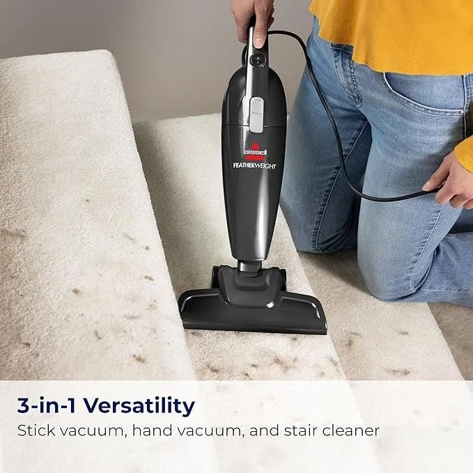 Black Bissell Featherweight Stick vacuum with crevice tool by Casavibeo, lightweight bagless design, suitable for quick cleaning.