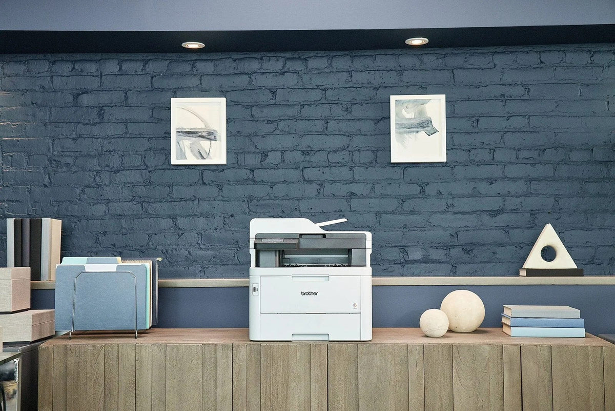 Brother MFC-L3780CDW wireless laser color printer with multiple paper trays and control panel, in a modern office setting