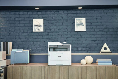 Brother MFC-L3780CDW wireless laser color printer with multiple paper trays and control panel, in a modern office setting