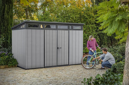 Grey Keter Cortina 9x7 ft. outdoor storage shed with Casavibeo branding, featuring double doors and a heavy-duty floor.