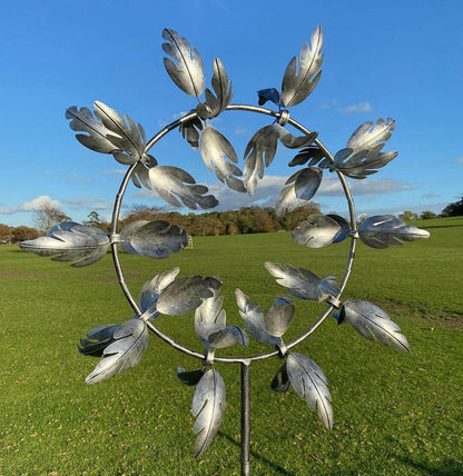 Colorful Belro metal windmill garden spinner spinning in the breeze, decorative kinetic wind sculpture for outdoor home and garden decor.