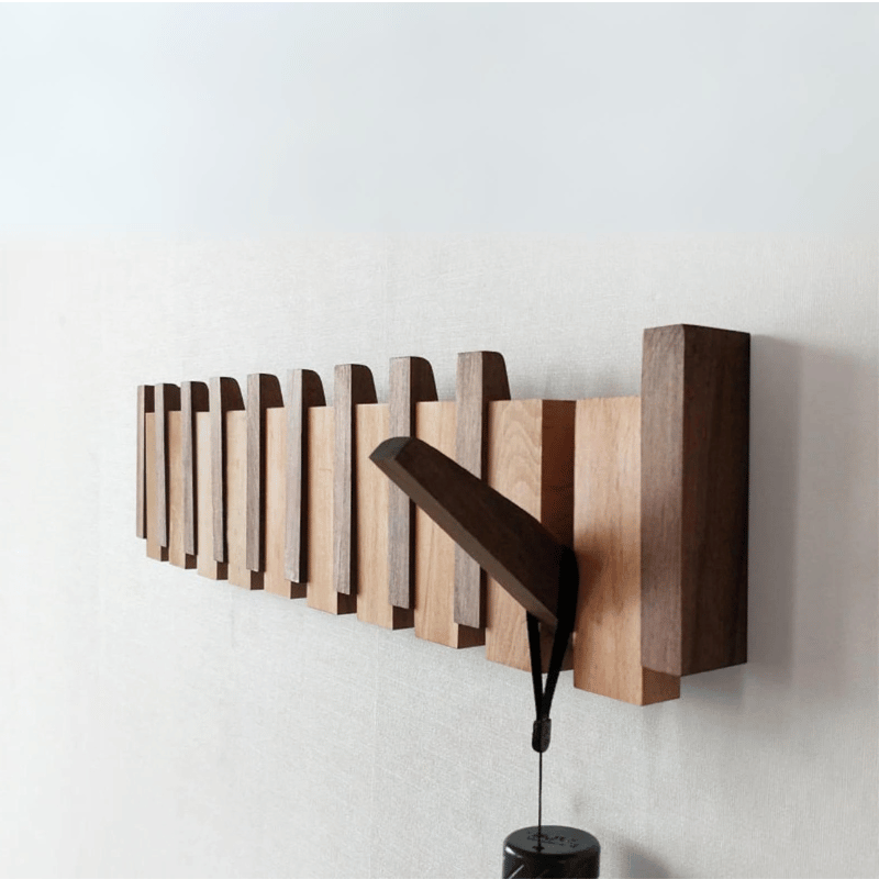 Handmade wooden coat rack by Belro with multiple hooks for jackets and coats, mounted on a wall in a cozy entryway.