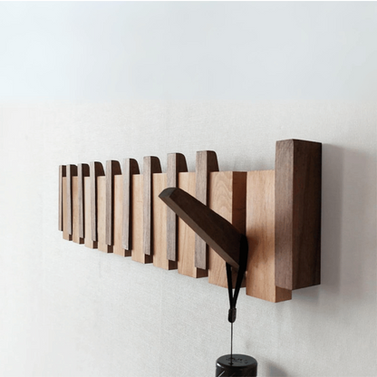 Handmade wooden coat rack by Belro with multiple hooks for jackets and coats, mounted on a wall in a cozy entryway.