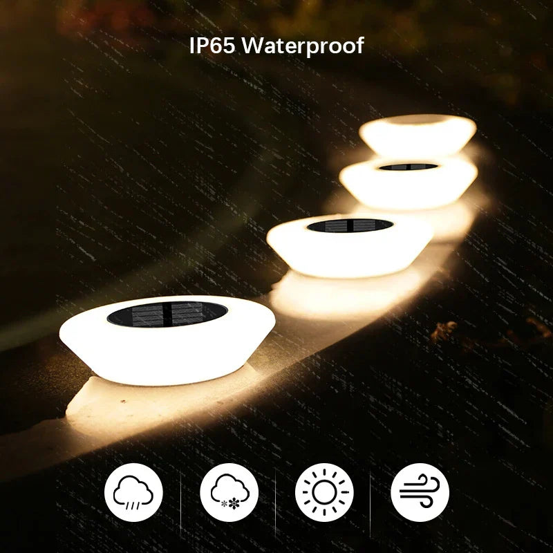 Mivoza solar ground light 4-pack with 14 LEDs and 360° illumination, installed on a garden pathway with ground spike mounts.