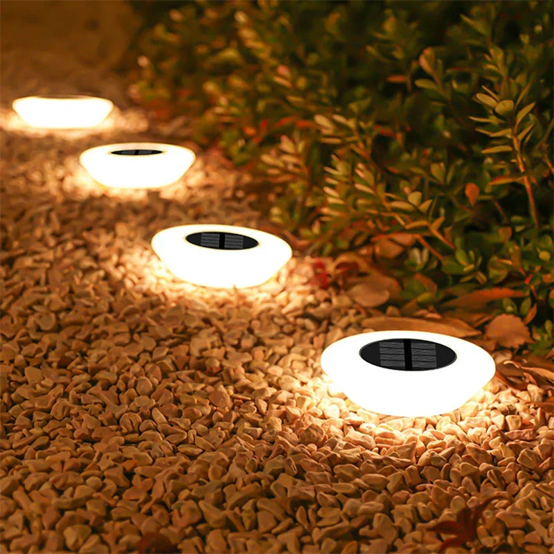 Mivoza solar ground lights 4-pack with 14 LEDs and 360° illumination, installed in garden ground spikes for outdoor lighting.