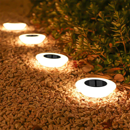 Mivoza solar ground lights 4-pack with 14 LEDs and 360° illumination, installed in garden ground spikes for outdoor lighting.
