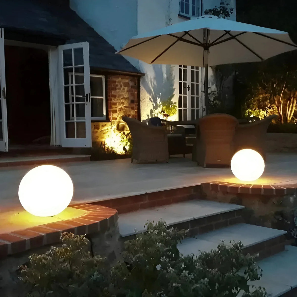 BowLift LumiGlobe weatherproof solar LED garden globe light glowing outdoors in a garden setting, spherical shape, outdoor illumination