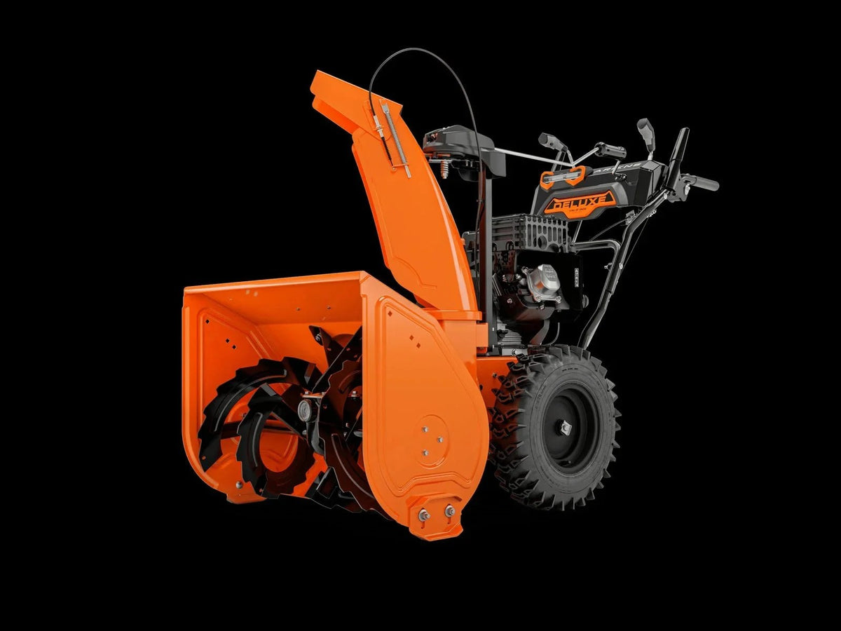 Ariens Deluxe 28-inch two-stage snow blower by Casavibeo, showing the snow clearing auger and chute in action on snowy terrain.