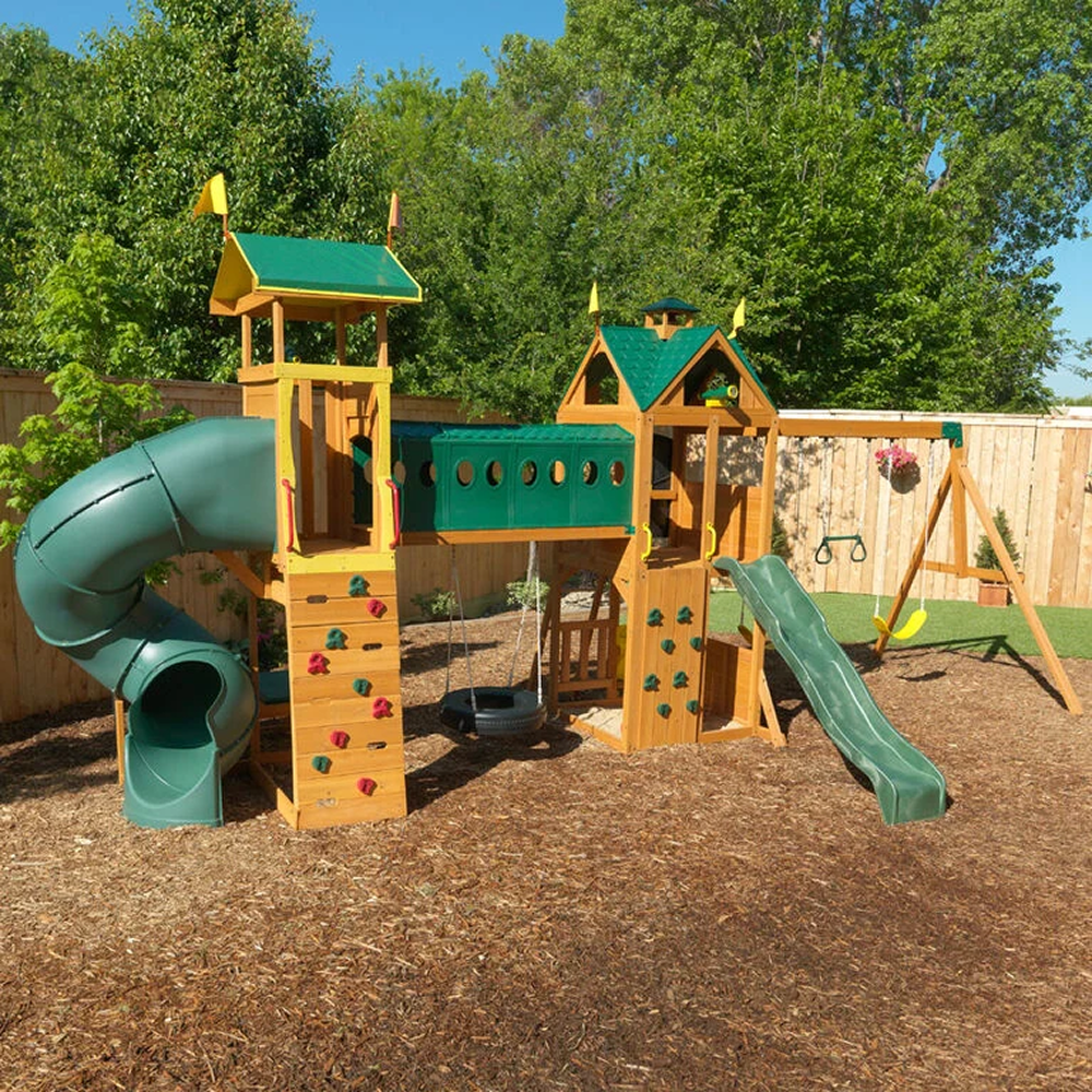 Casavibeo KidKraft Mockingbird View cedar swing set with lookout tower, tube slide, and basketball hoop in a backyard setting.