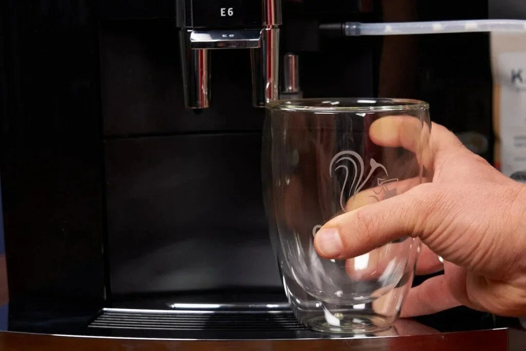 Casavibeo Jura E6 automatic coffee machine with sleek design, coffee spouts, display panel, and brewing area visible in the image.