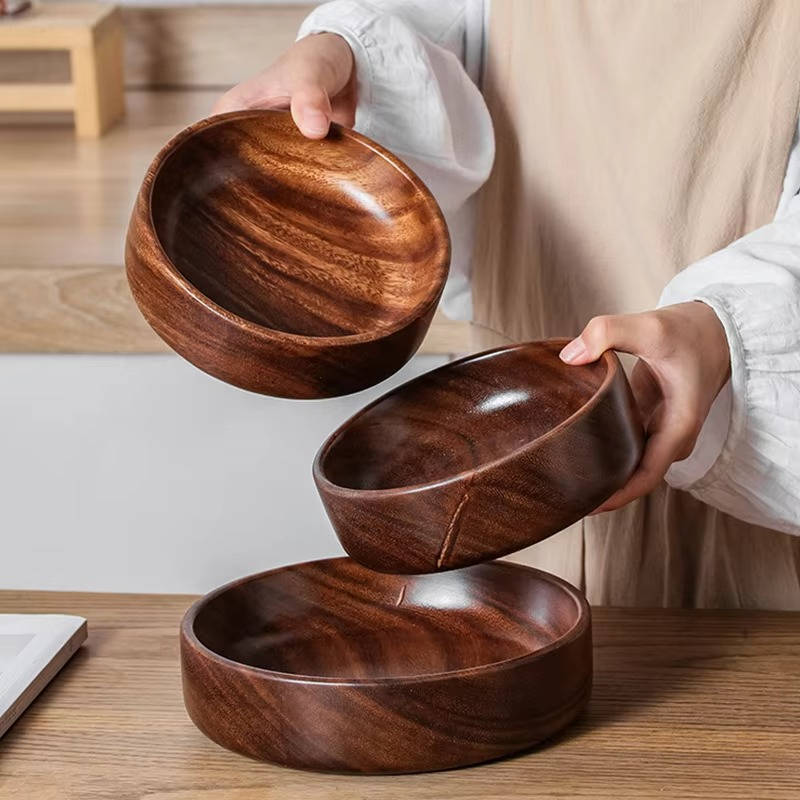 Handcrafted wooden bowls for food by Belro, displayed with fresh fruits and salads in a kitchen setting.