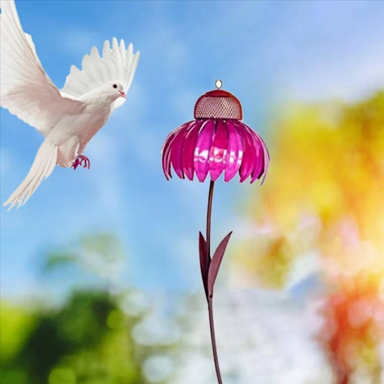 Belro outdoor flower bird feeder hanging from a garden branch with colorful flowers in the background.