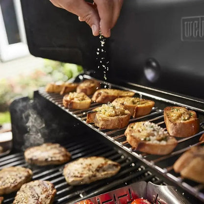 Casavibeo Weber Genesis E-325s gas grill with four burners, stainless steel lid, side shelves, and control knobs.