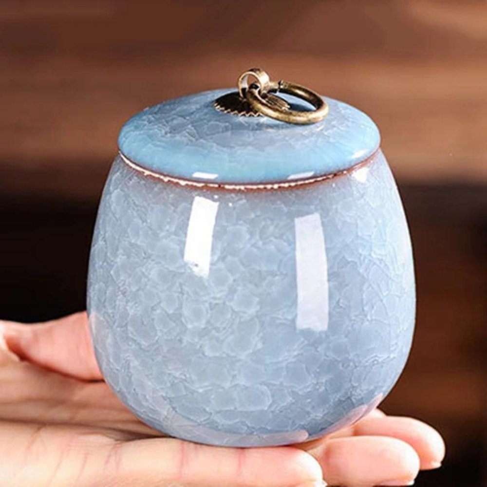 Handcrafted ceramic pet urn for dogs and cats with a smooth, glossy finish, featuring engraved paw prints and floral accents.