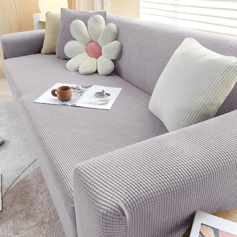 Stretchable Belro sofa cover in neutral fabric fitted over a modern sofa for a fresh, clean look in the living room.