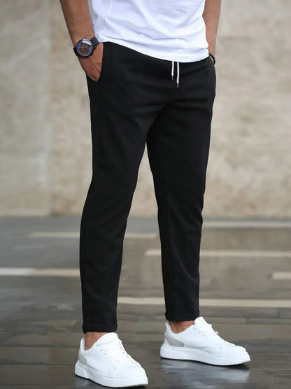 Men's stretch pants by Belro, showing a close-up of the dark, fitted trousers with a smooth waistband and slim fit design.