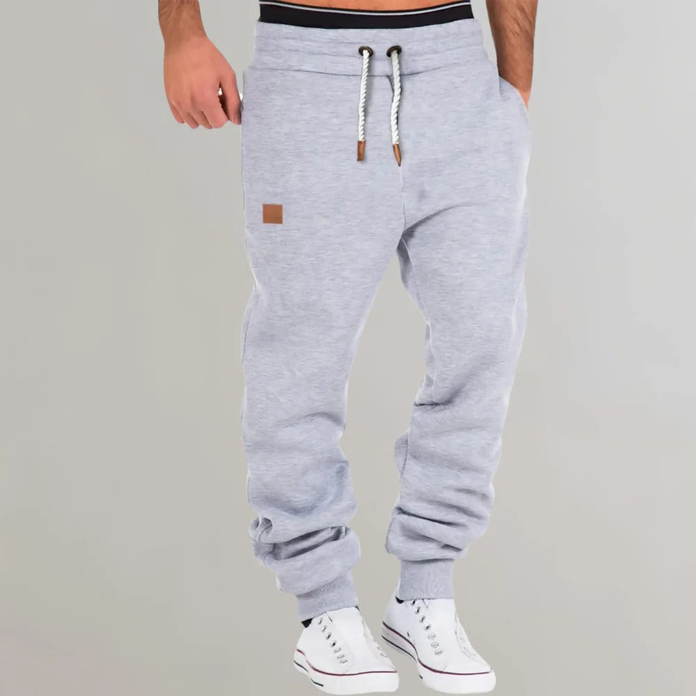 Men's Belro jogging pants in black, made of lightweight activewear fabric, shown on a model standing outdoors.