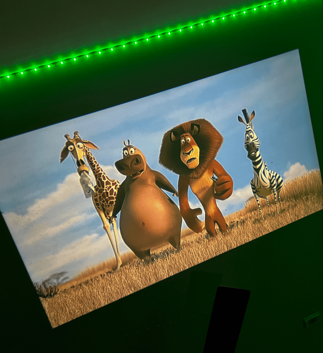 Belro Mini Movie Projector displaying a bright image on a wall, compact electronic device for home entertainment.