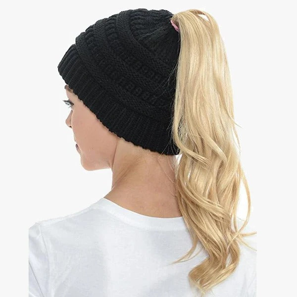 Belro Ponytail Beanie with a ribbed design, featuring a messy bun hole and solid color, worn by a woman.