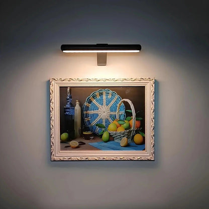 Wireless LED picture light by Belro mounted on a wall, illuminating artwork in an outdoor home and garden setting.