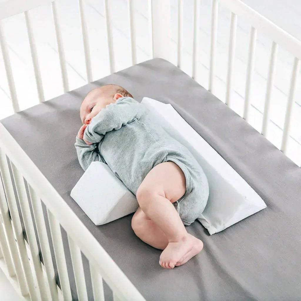 Belro newborn side sleeper wedge pillow for infants, soft fabric cover, designed to provide safe positioning in a crib or bed.