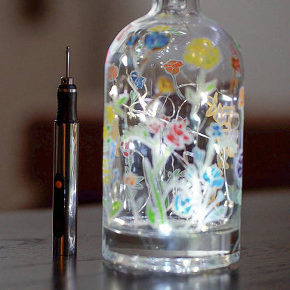 Belro engraving pen used on clothing fabric, close-up of customized design with a glass surface, demonstrating precise engraving technique.