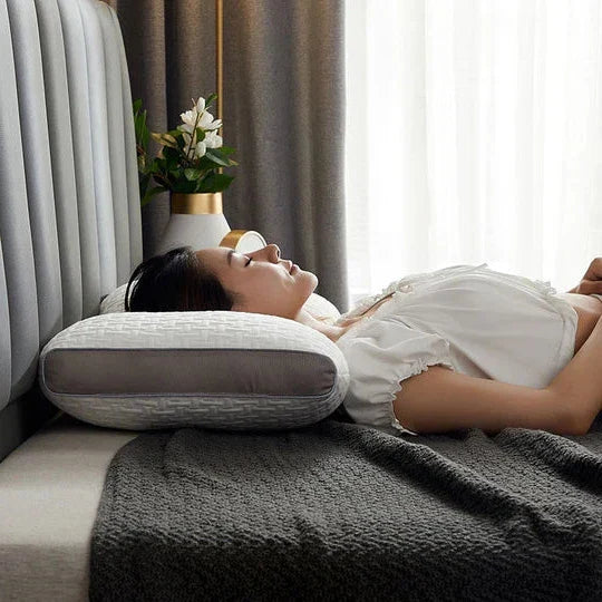 Belro hybrid pillow for back and side sleepers, providing neck and shoulder support, shown in a neutral color on a bed.