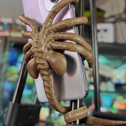 Belro Horrible Facehugger phone holder mounted on a desk, showcasing its creepy alien-inspired design for phone mounting.
